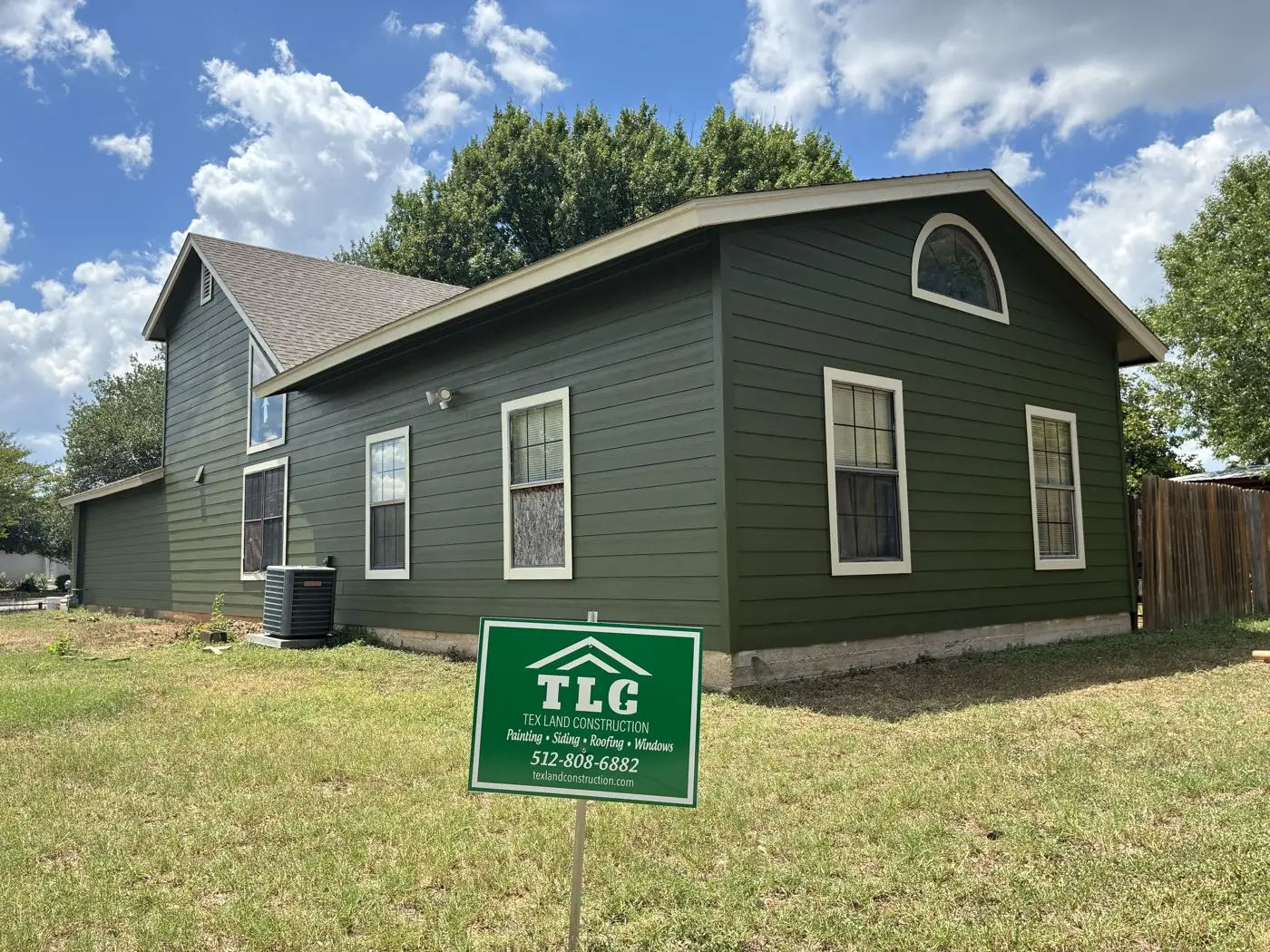 Rear elevation of an Austin TX home finished in dark green with new white-trimmed glass units
