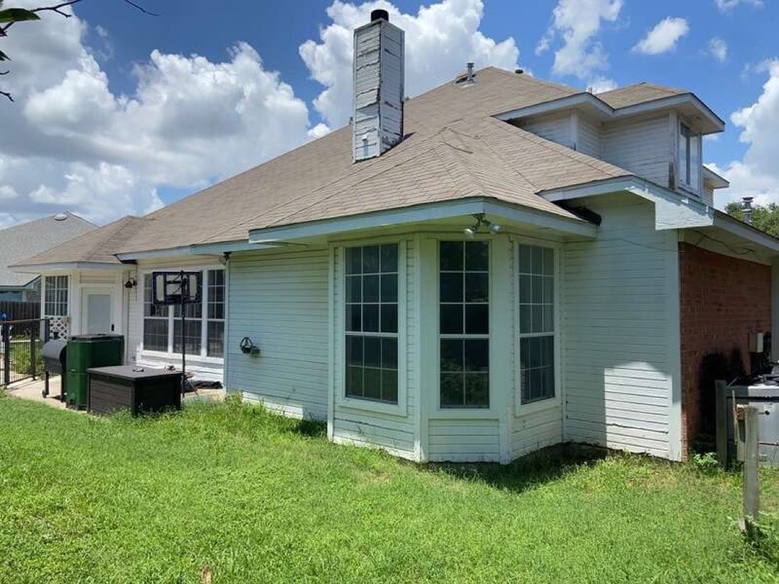 Weathered bay window with wood grids on a pale green Austin TX home before replacement