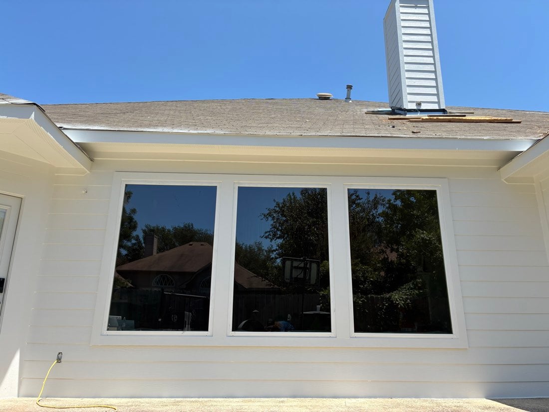 Large glass door and window unit on the rear elevation of an Austin TX home with white siding