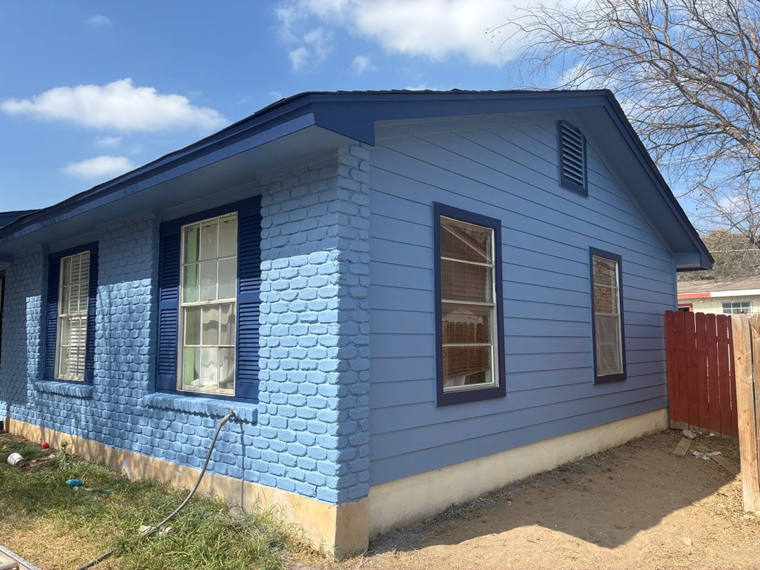 Blue brick ranch home in Austin TX after new single-hung windows and navy trim were installed by Tex Land Construction