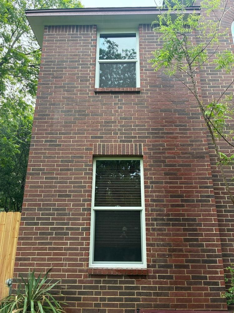 Two single-hung replacement windows with brick sills on a two-story red brick home in Austin TX