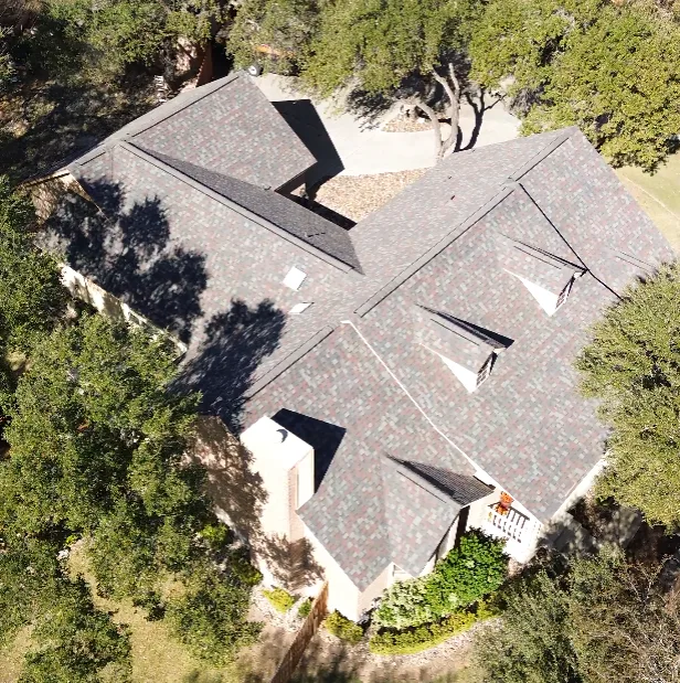 Aerial view of a large shingle roof among trees