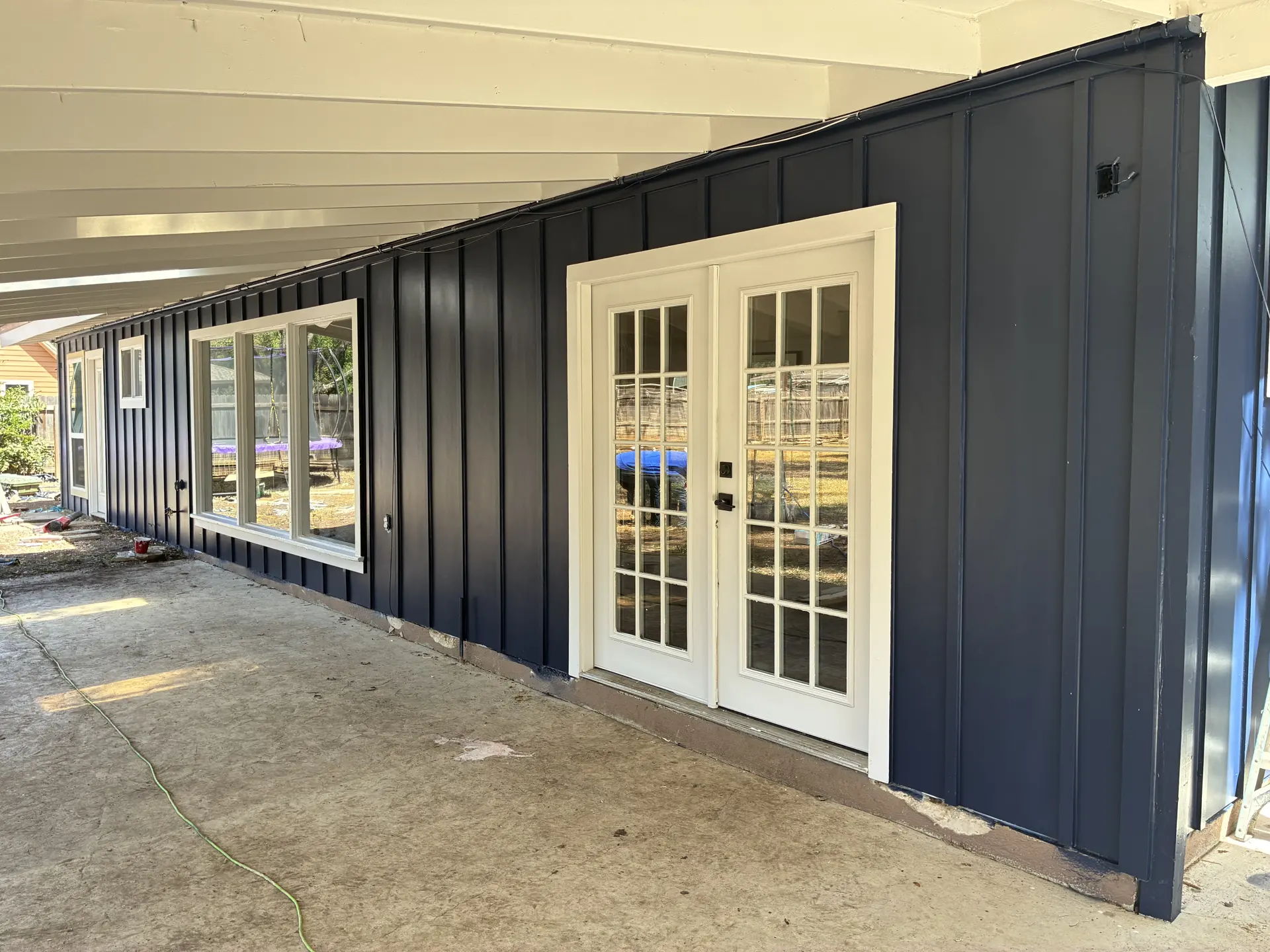 Dark blue vertical siding beside white patio doors