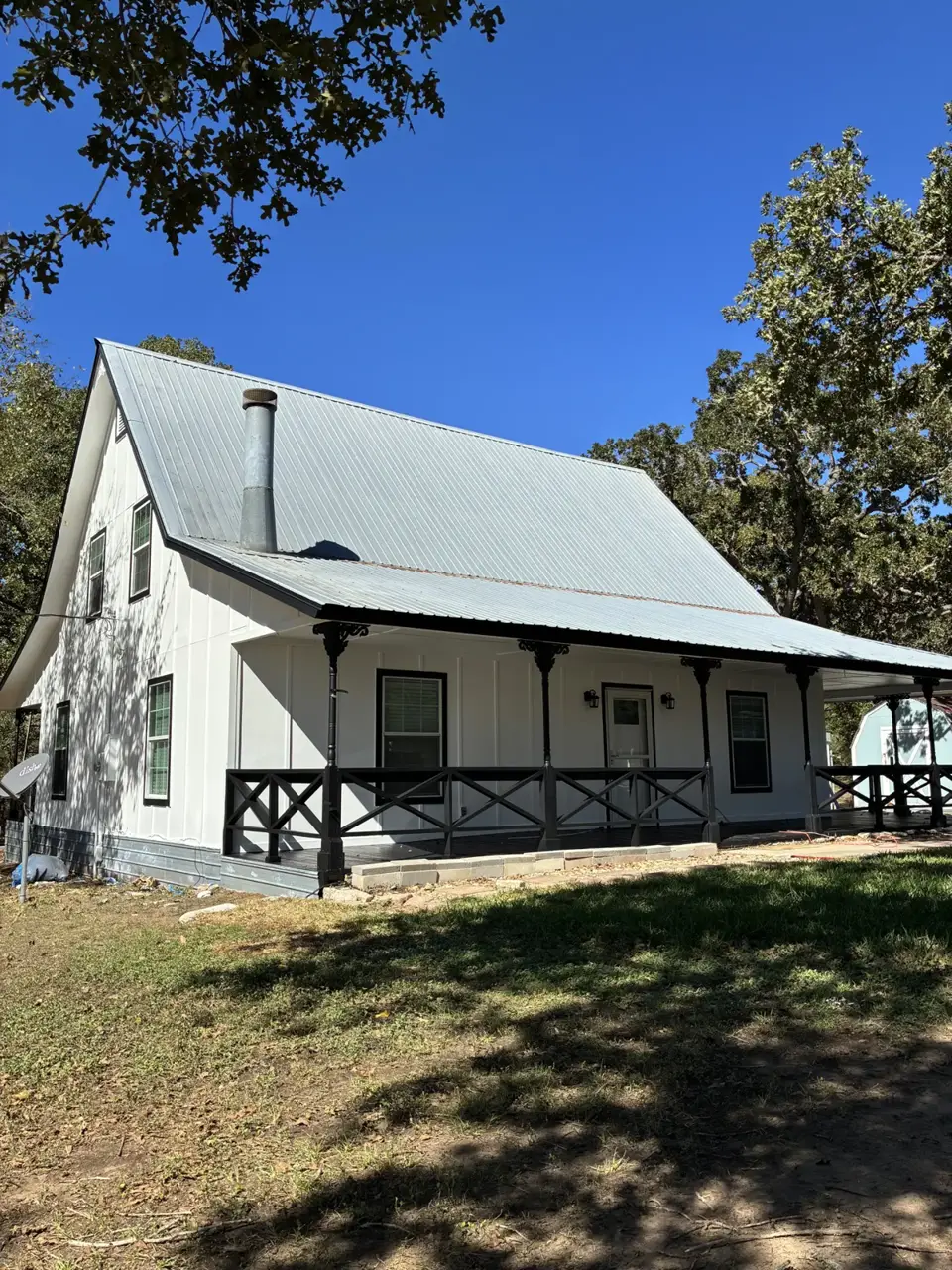 White cottage with vertical siding and a covered porch