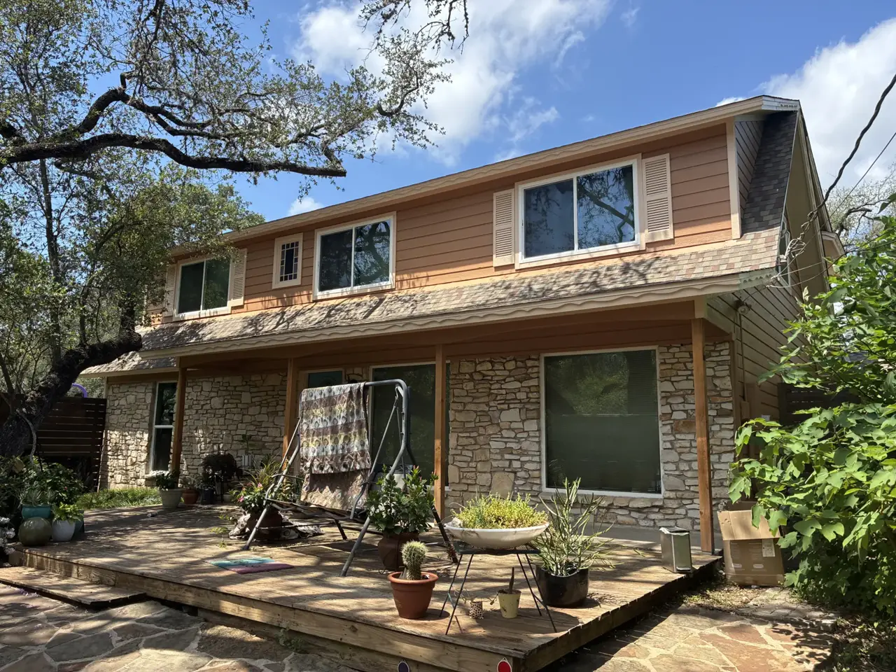 Brown siding and large windows above a stone exterior