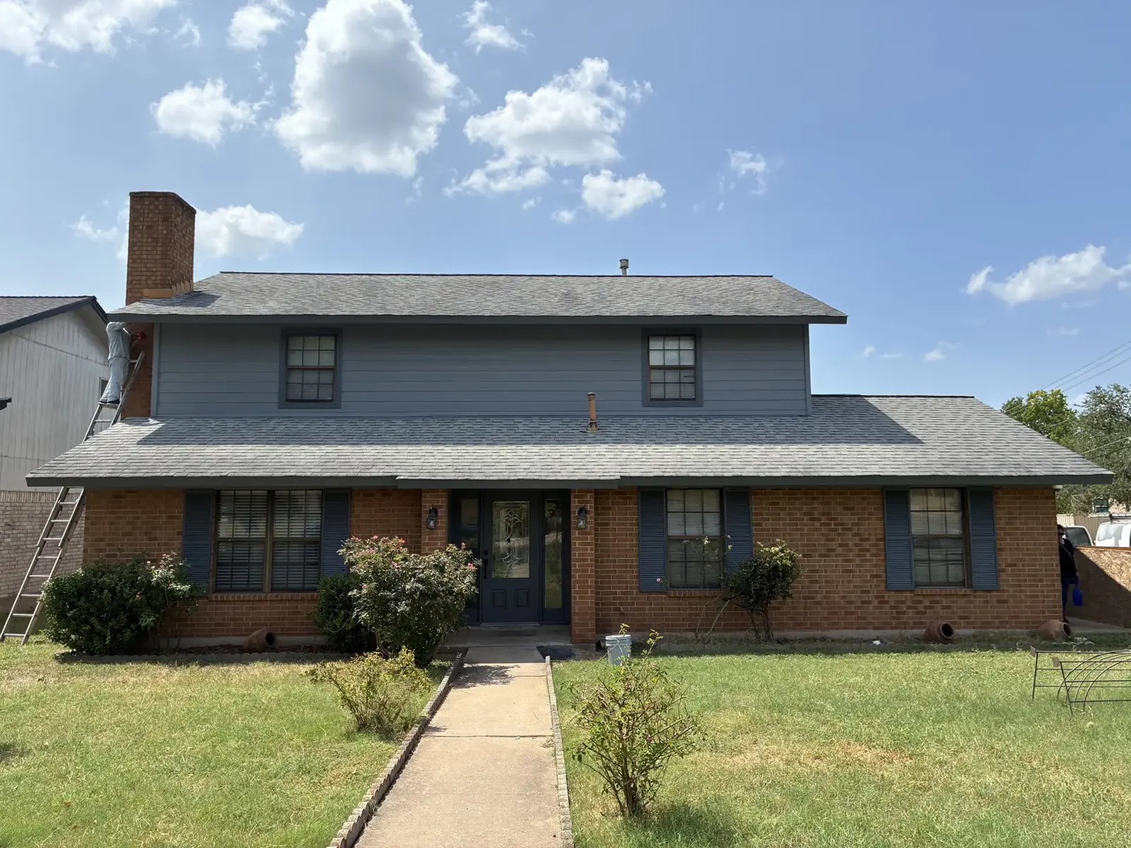 Two-story house with gray siding and brick below
