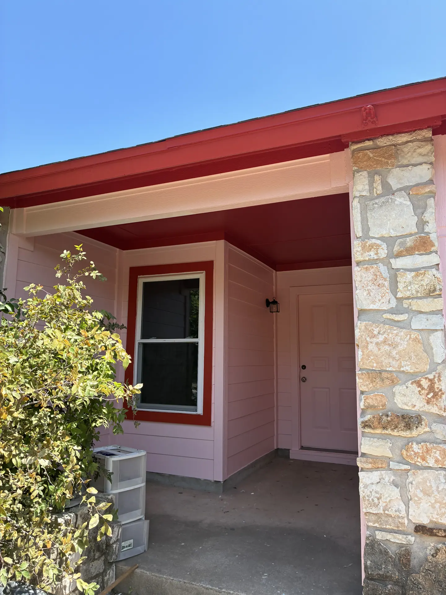Pink siding with red window trim and stone accents
