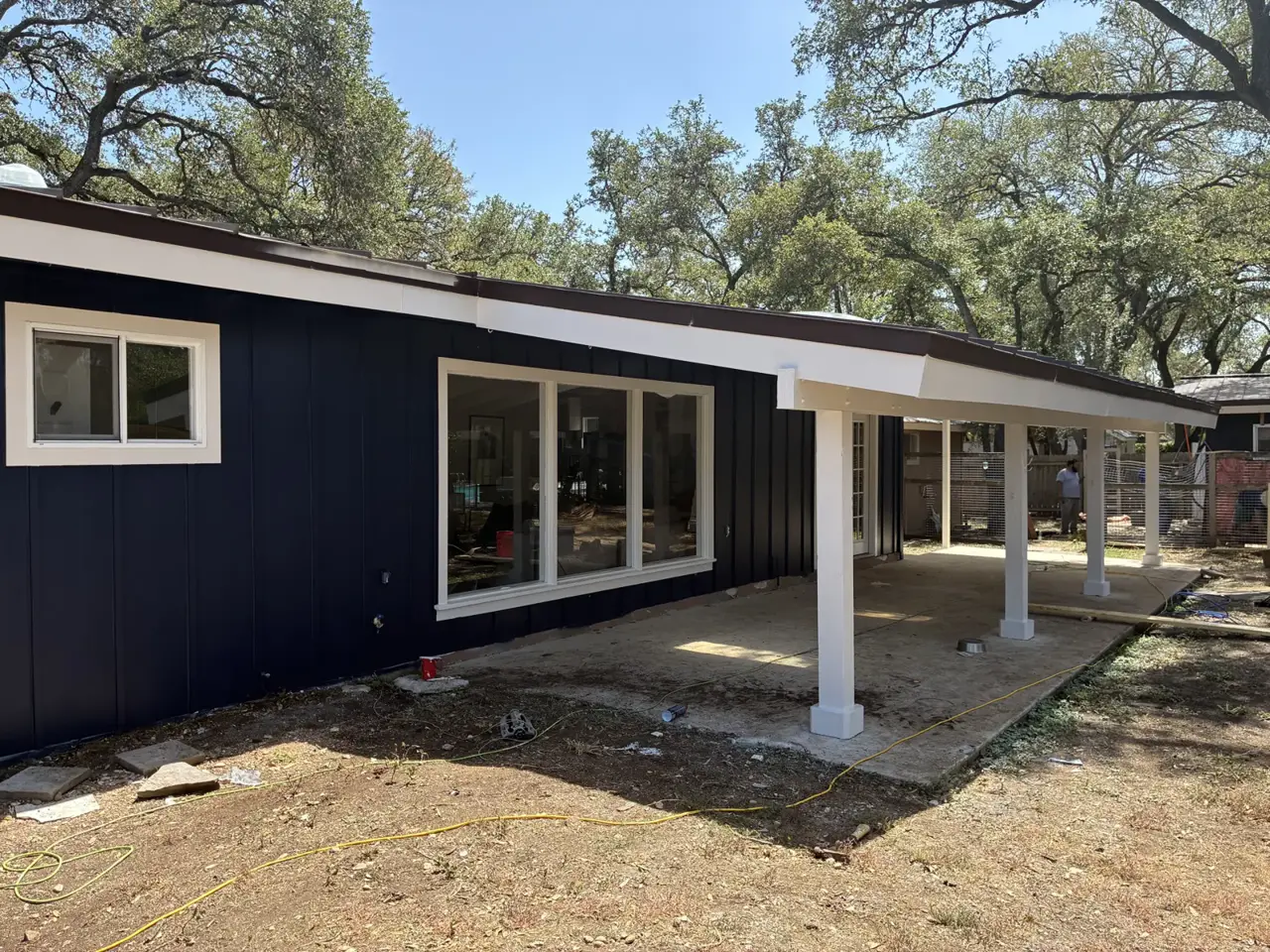 Dark vertical siding and white posts around a patio