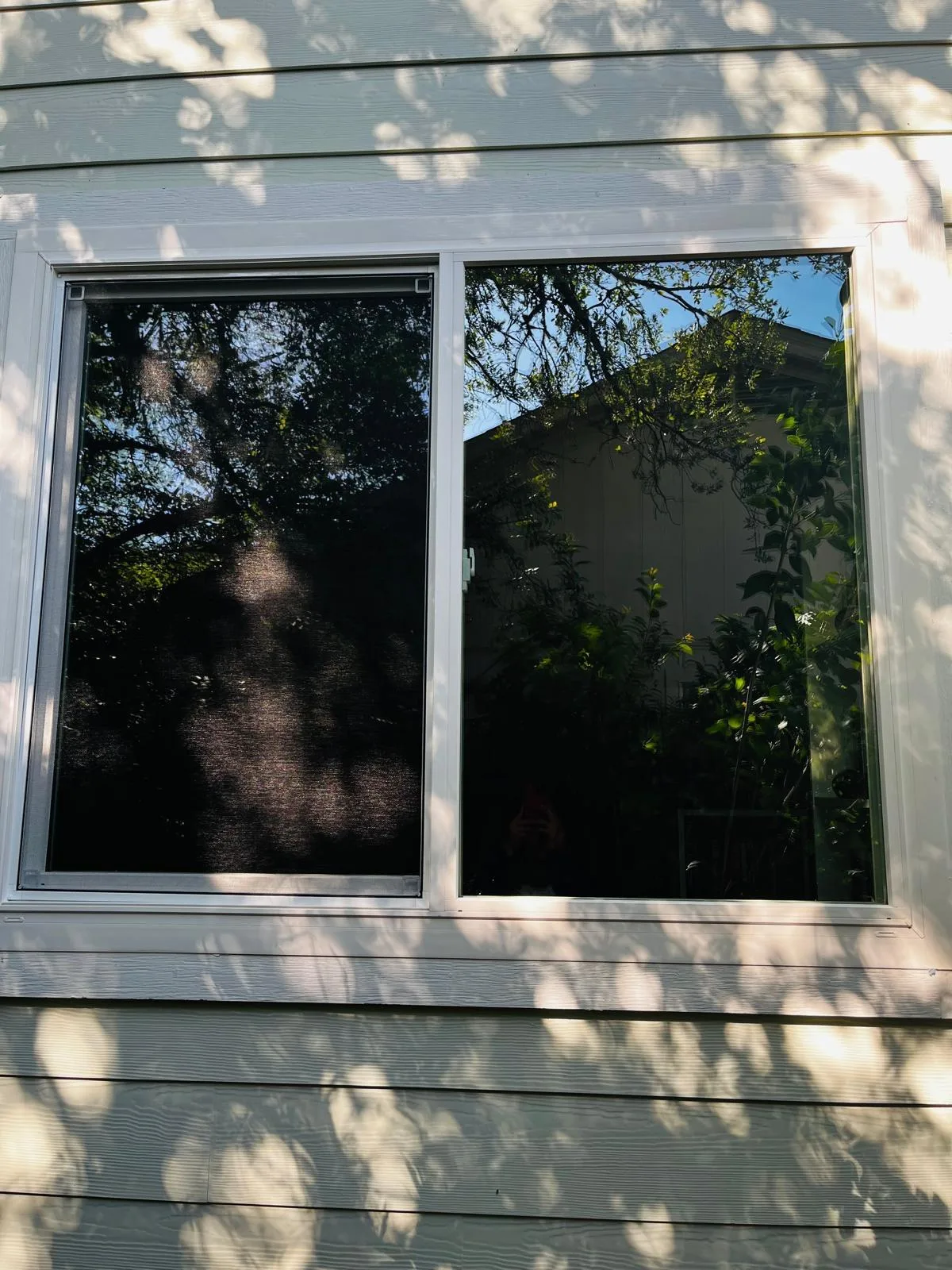Large rectangular window with white trim in pale siding