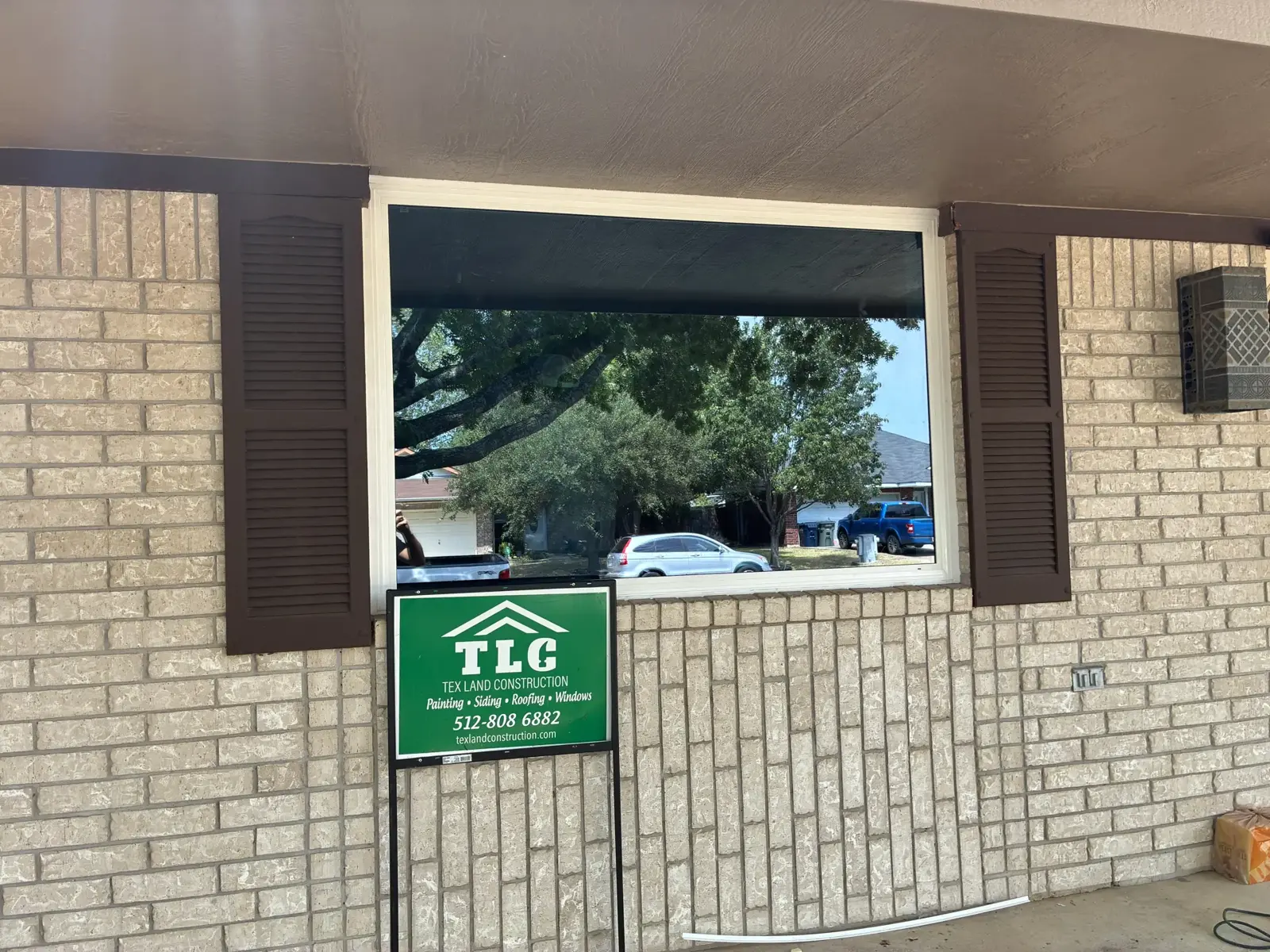 Picture window in a brick wall beside a company sign