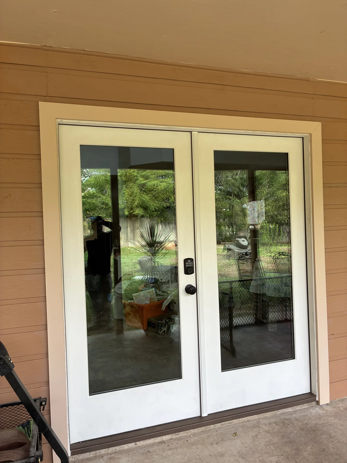 White framed glass patio doors in brown siding